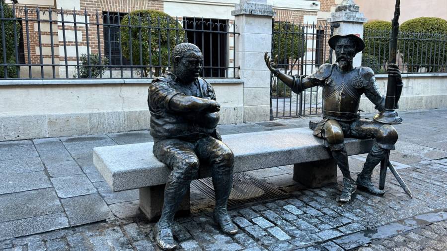 Estatuas de bronce de Don Quijote y Sancho Panza sentados en un banco del municipio