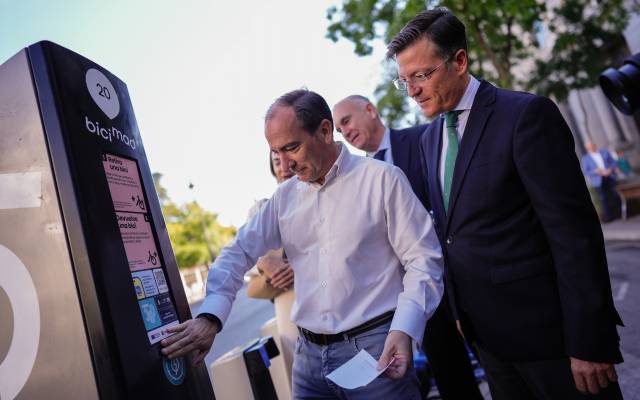 El delegado de Urbanismo, Medio Ambiente y Movilidad, Borja Carabante, junto con el concejal delegado de Limpieza y Zonas Verdes, José Antonio Martínez Páramo, coloca el nuevo distintivo que lucirán las estaciones de Bicimad en la estación de Banco de España