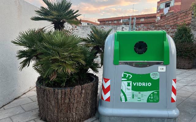 Un hombre deposita un envase en un contenedor de vidrio