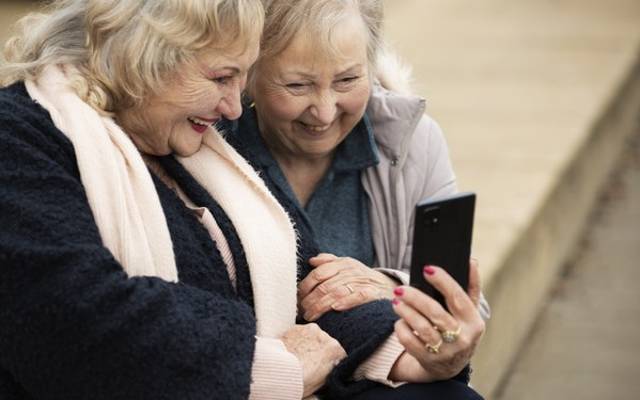 Imagen de recurso de dos personas mayores mirando la pantalla de un teléfono móvil