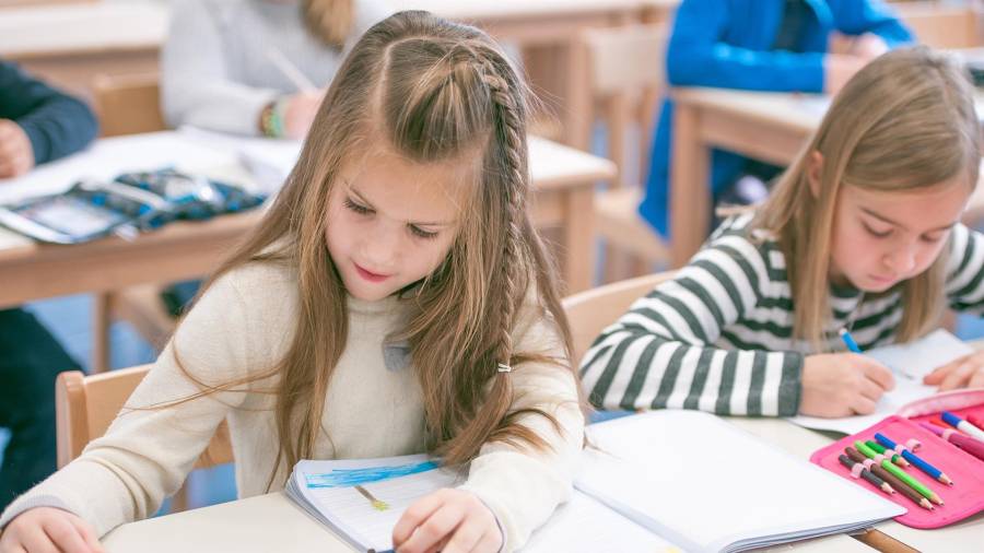 Dos niñas realizan tareas de dibujo sobre una mesa