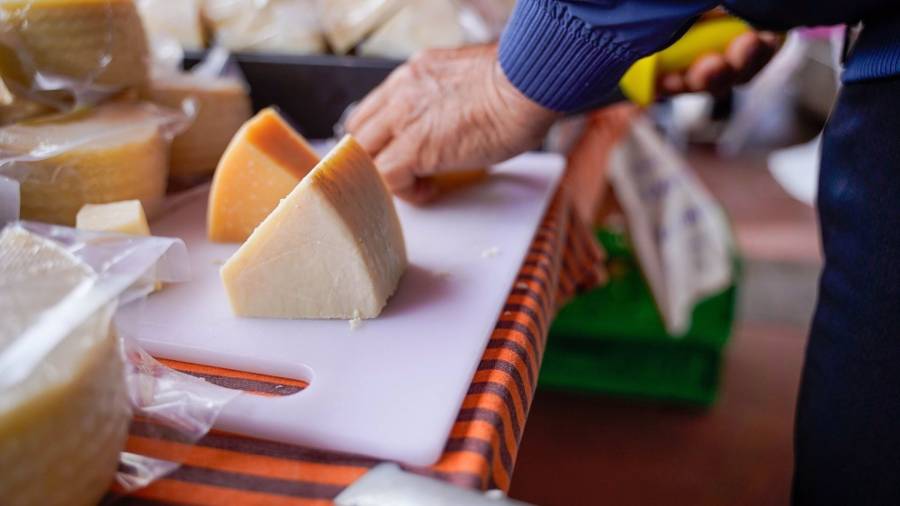 Una persona corta una cuña de queso sobre una tabla