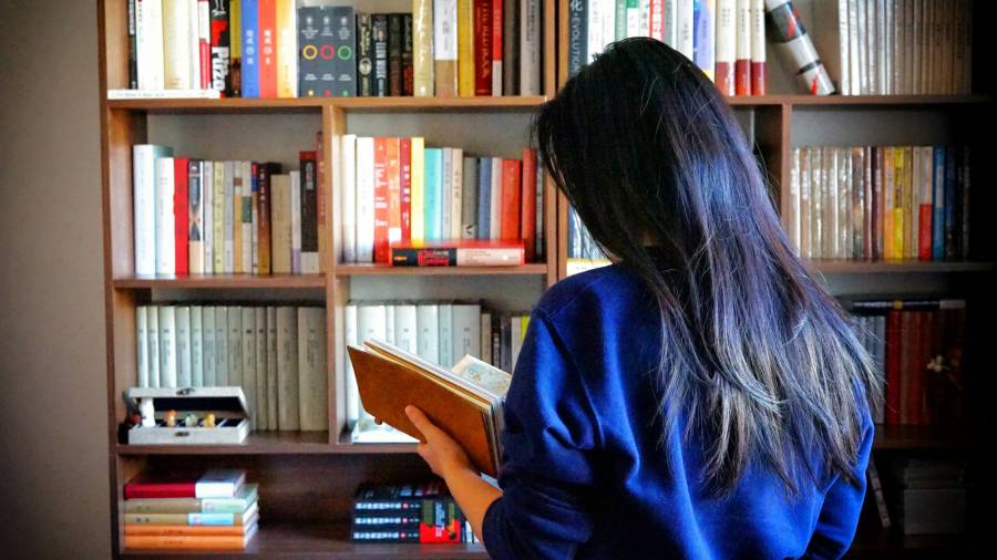 Imagen de recurso de una persona frente a una estantería llena de libros