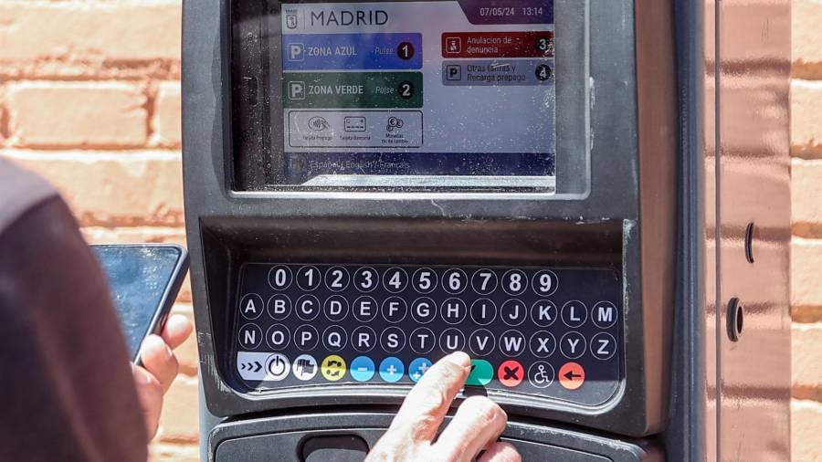 Una persona utiliza un parquímetro