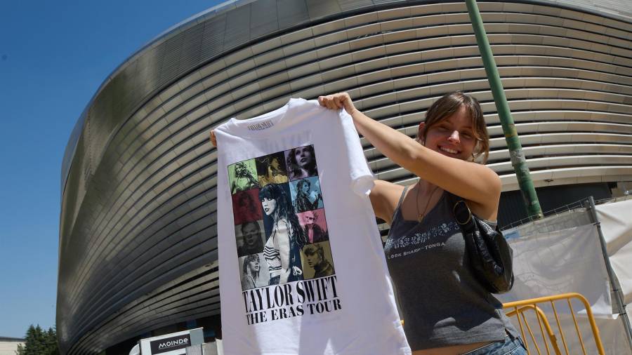 Una mujer sujeta una camiseta de merchandaising, en los alrededores del Estadio Santiago Bernabéu