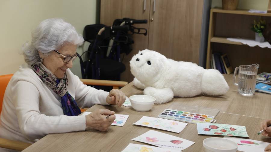 Usuaria del Centro de Día Municipal María Teresa León, en Chamberí, con el robot terapéutico Nuka