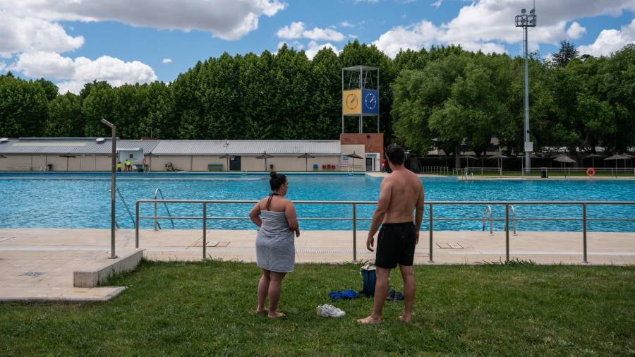 Dos personas salen de la piscina en el primer día de apertura para el público debido a la bajada de temperaturas, en la piscina municipal de Puerta de Hierro, a 13 de mayo de 2023