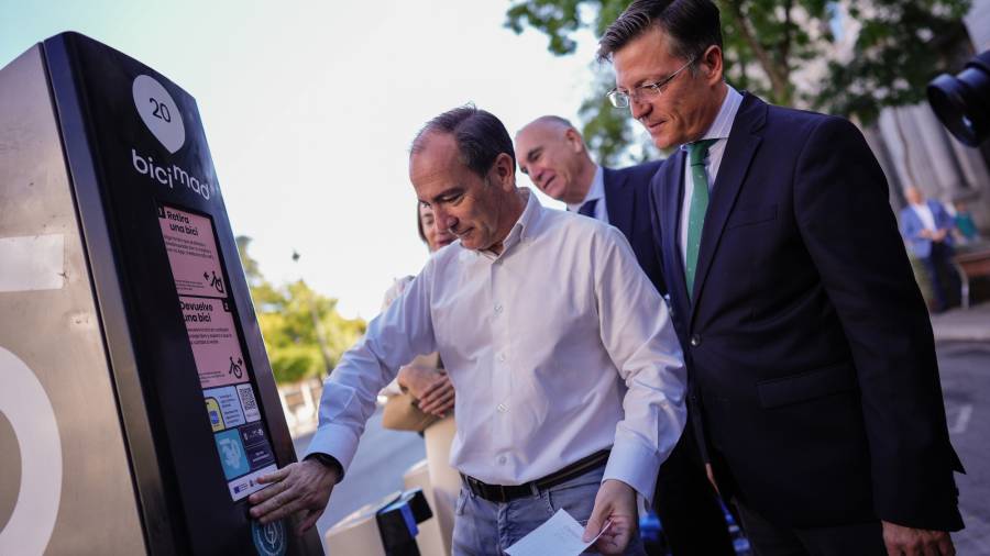 El delegado de Urbanismo, Medio Ambiente y Movilidad, Borja Carabante, junto con el concejal delegado de Limpieza y Zonas Verdes, José Antonio Martínez Páramo, coloca el nuevo distintivo que lucirán las estaciones de Bicimad en la estación de Banco de España