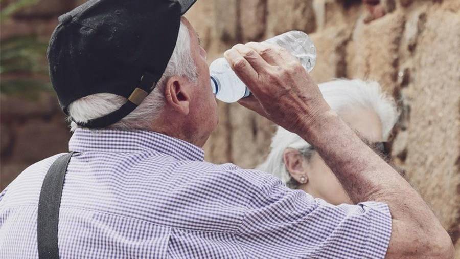 Una persona mayor bebe agua para hidratarse