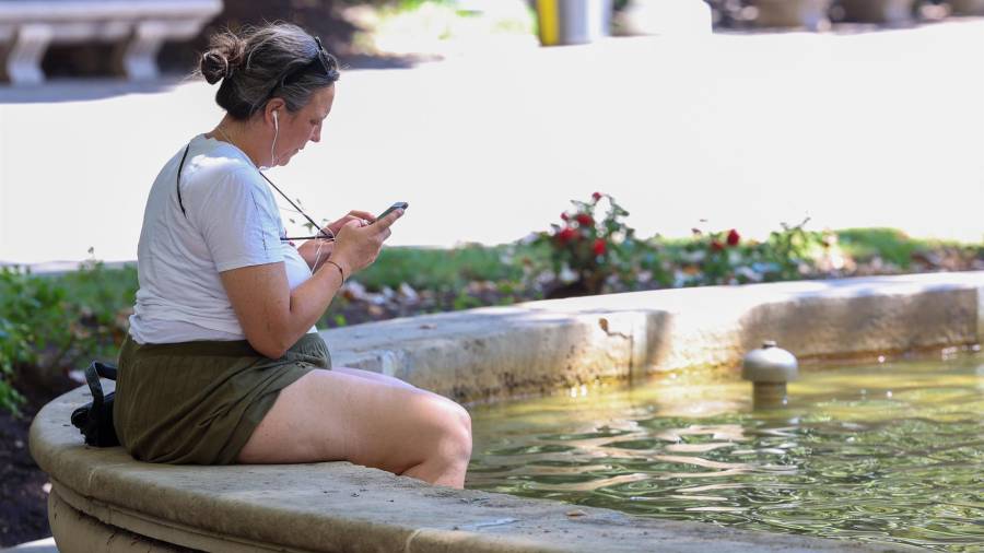 Una mujer con los pies metidos en una fuente durante una segunda ola de calor