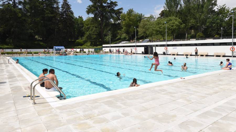 Varias personas se bañan y toman el sol, en la piscina municipal de Casa de Campo