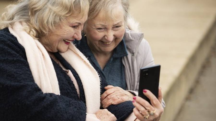 Imagen de recurso de dos personas mayores mirando la pantalla de un teléfono móvil