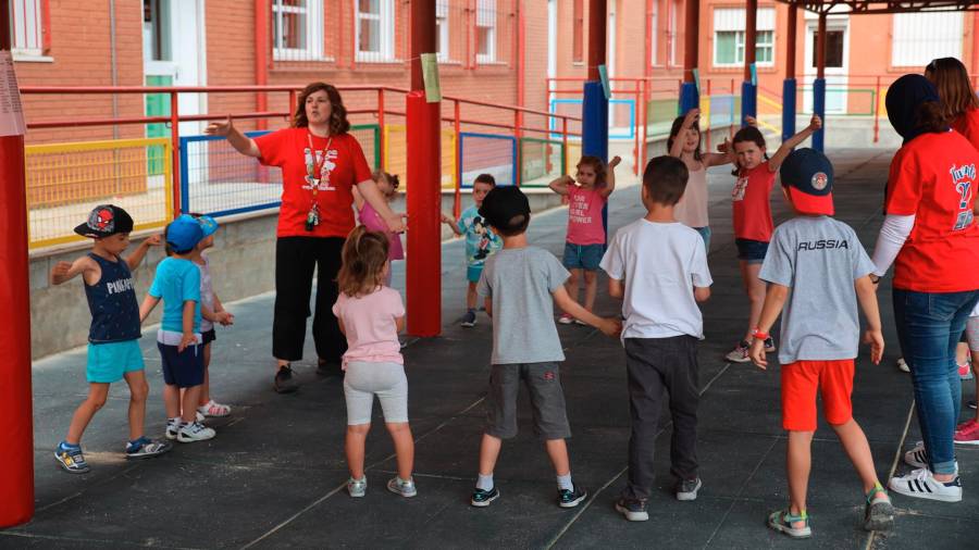 Niños y niñas en un patio de colegio realizando actividades con monitoras